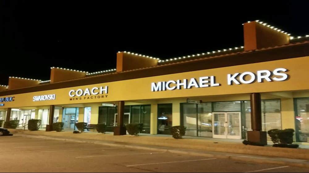 Shopping center storefronts with warm white roofline Christmas lights